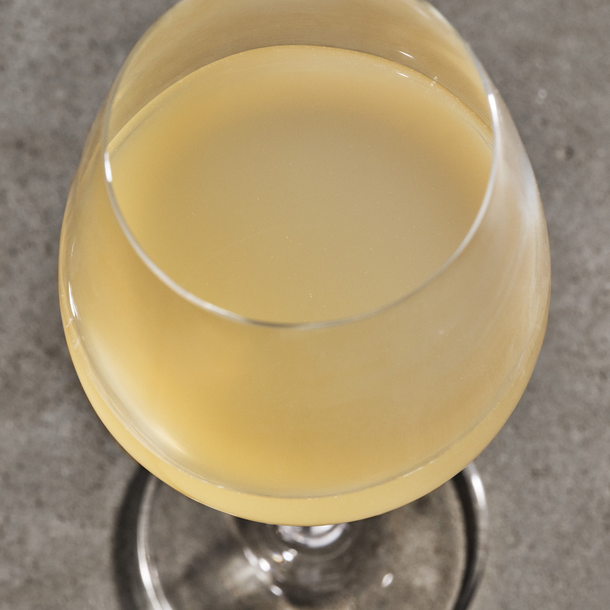 Glass of yellow liquid on a gray surface