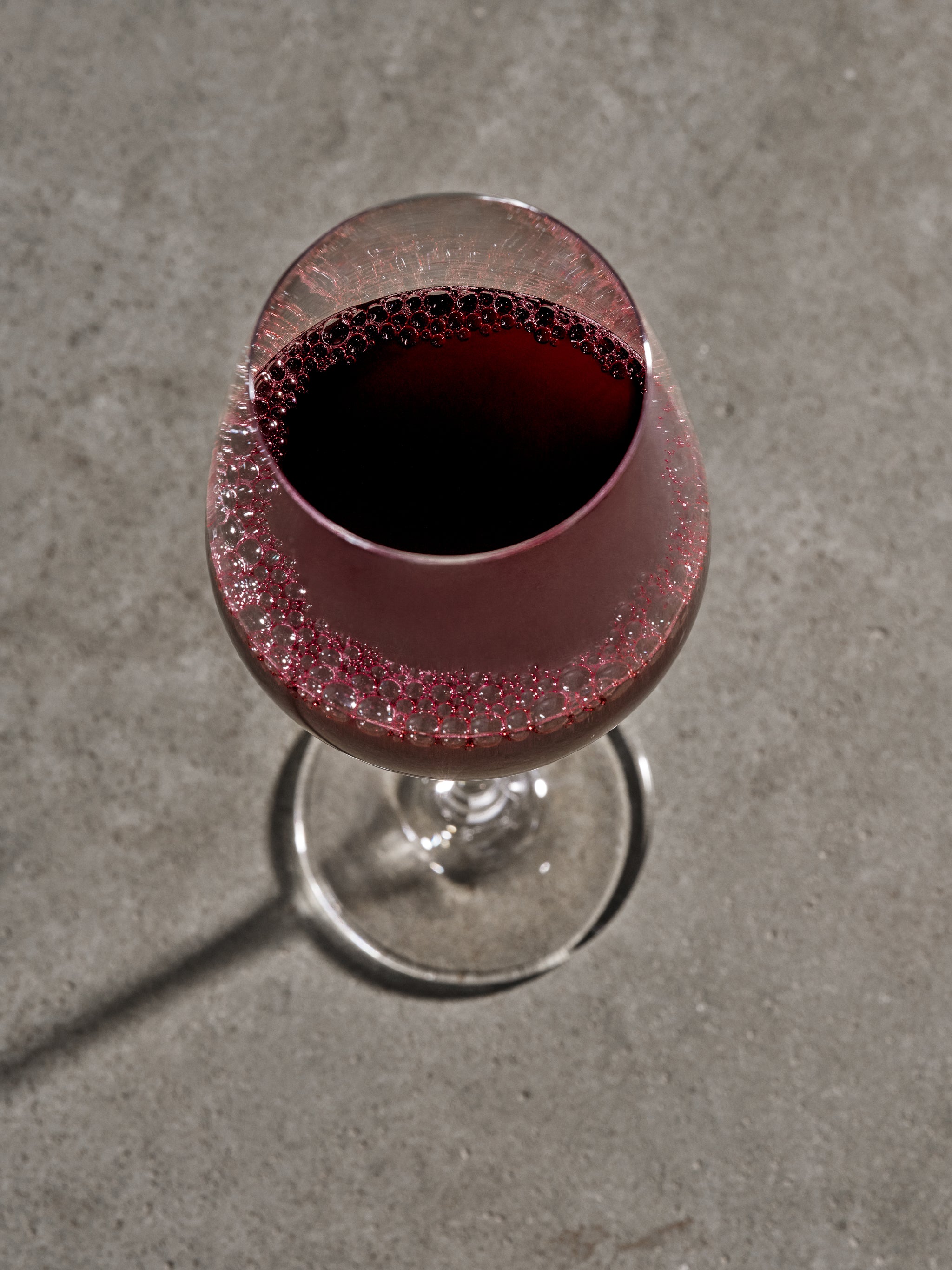Glass with red liquid on a gray concrete surface. New Forms from MURI