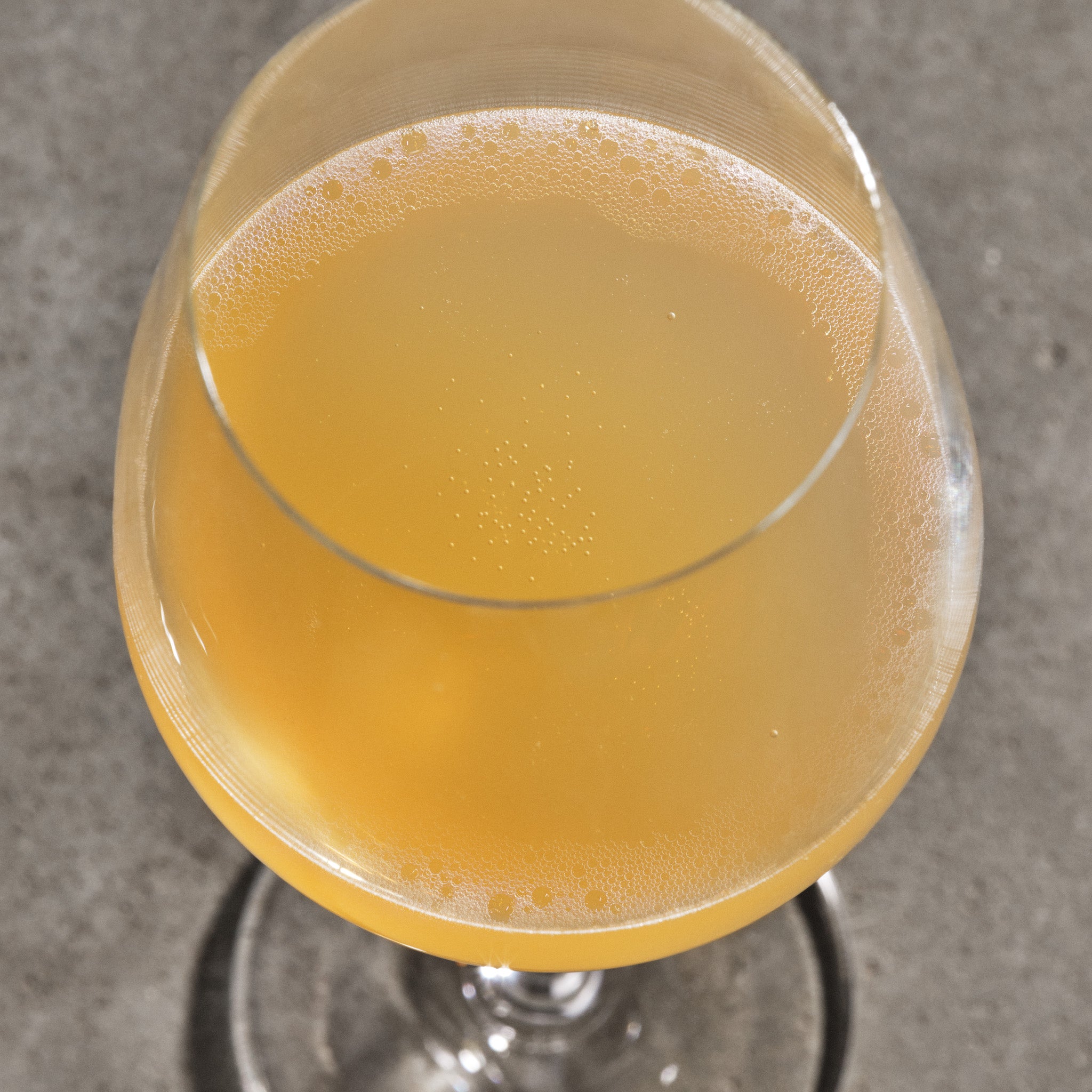 Close-up of a glass with a yellowish beverage on a gray surface